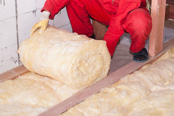 Person rolling out insulation to install it into an industrial building floor in Norwalk, CT.