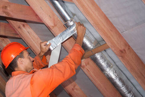 Person install insulation on a heating duct in a Norwalk, CT attic.