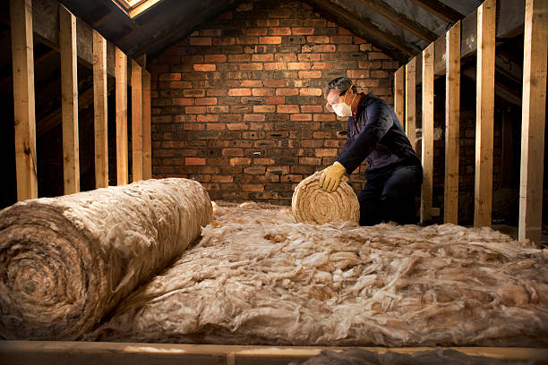 Person rolling out insulation for an attic floor in Norwalk, CT.
